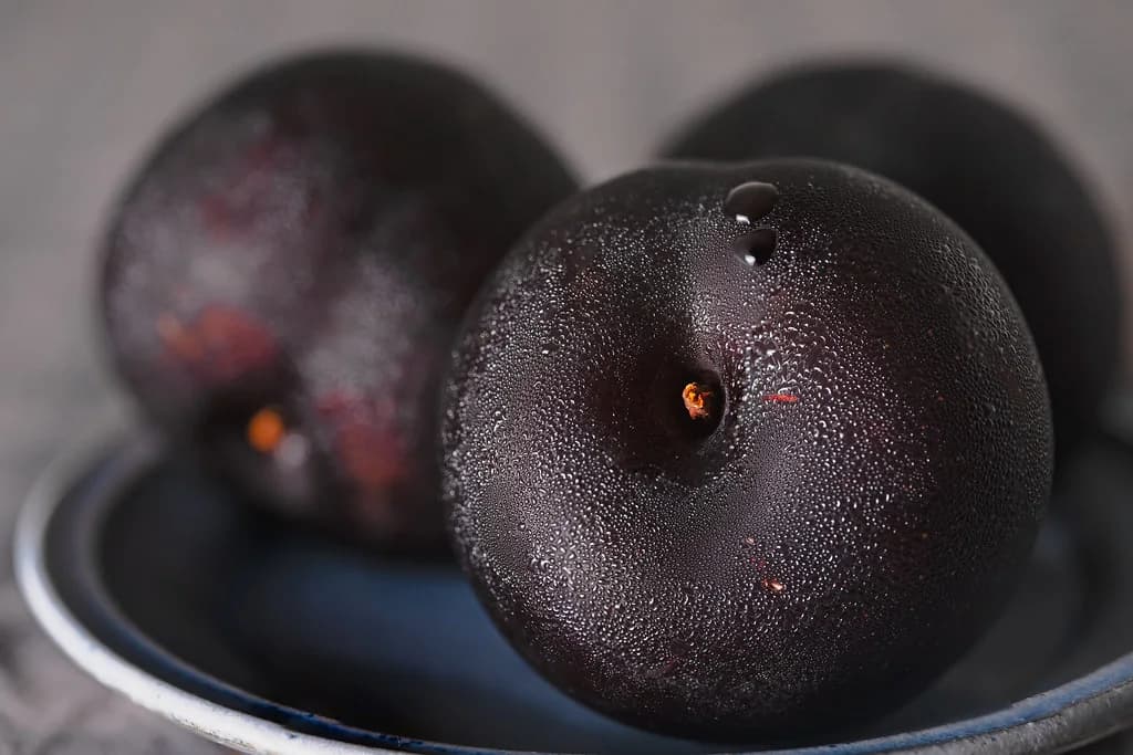Ripe dark plums in a bowl